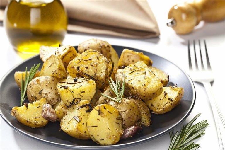 Home Gehalveerde gebakken aardappelen met knapperige bruine snijkant op bakplaat, klaar om in korte tijd te bakken